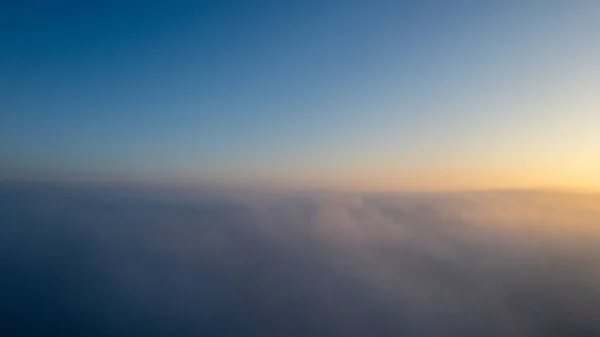 Вид з повітря. Летючи в тумані, летить в тумані над ранковими хмарами на сході сонця. Повітряна камера. Політ над хмарами до сонця з туманними хмарами, що пролітають повз. Похмура погода — стокове фото