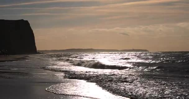 Güneşin sıcacık ışığıyla bir sahilde dalgalar koparken güzel ve rahatlatıcı okyanus gün batımı suya yansıyor. — Stok video