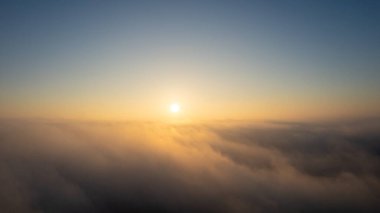 Hava görüntüsü. Sis içinde uçmak, güneşin doğuşundaki sabah bulutlarının üzerinde uçmak. Hava kamerası görüntüsü. Bulutların üzerinden güneşe doğru uçarken sis bulutları yüzüyor. Sisli hava