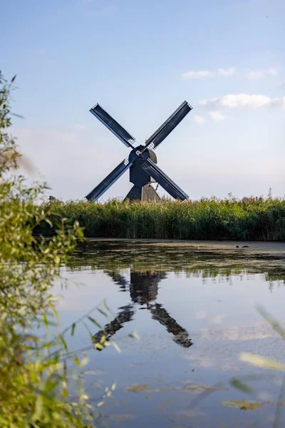 Verticaal beeld van een van de beroemde Nederlandse windmolens bij Kinderdijk, een UNESCO werelderfgoed. Op de foto staat de enige zwarte molen van de 19 windmolens bij Kinderdijk, Zuid-Holland — Stockfoto