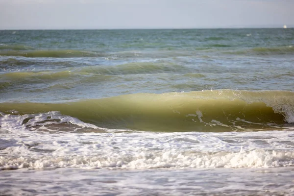 Botsende golven klapperend op het zandstrand de een na de ander onder een blauwe zonsondergang hemel, selectieve focus gebruikt. — Stockfoto