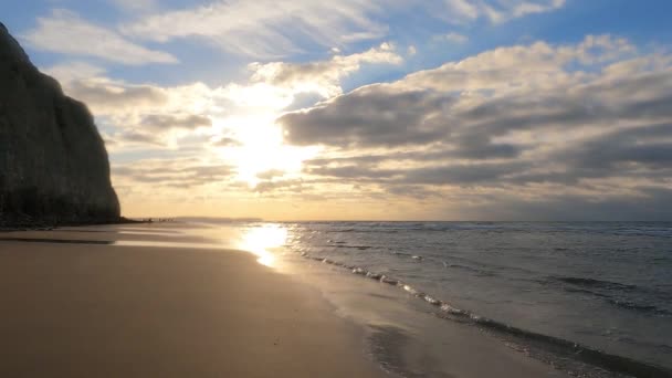 Verbazingwekkende kleurrijke zonsondergang met golven op een zandstrand aan de zee onder een hemel geschilderd met wolken en een gouden zon. Schilderachtig natuurlandschap.Wolken weerspiegeld in water. Zen-achtige rust — Stockvideo