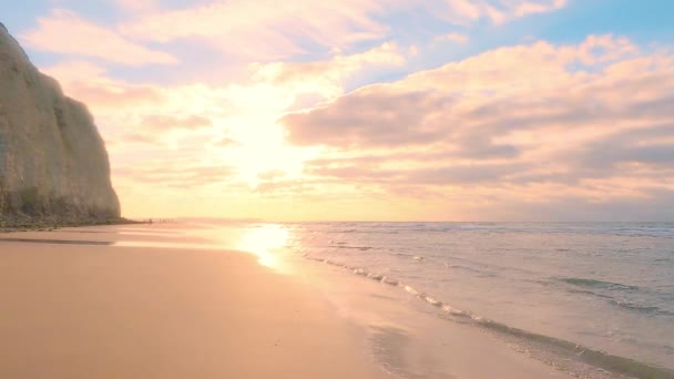 Csodálatos színes naplemente hullámok jönnek a homokos tengerparton az ég alatt festett felhők és egy arany nap. Festői természeti táj.Felhők tükröződnek a vízben. Zen-szerű nyugalom — Stock videók