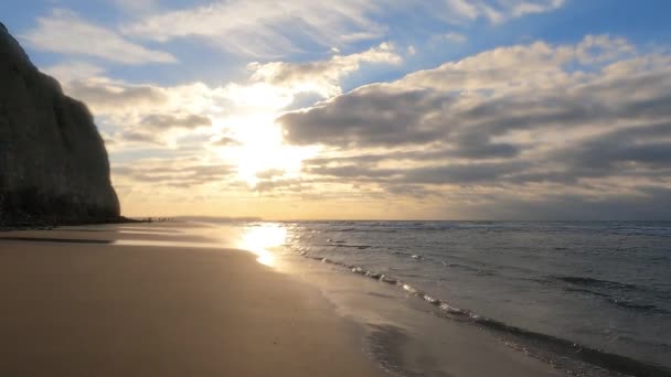 Дивовижний барвистий захід сонця з хвилями, що приходять на піщаний пляж біля моря під небом, намальованим хмарами і золотим сонцем. Мальовничі природні пейзажі. Хмари відбиваються у воді. Дзен-подібний спокій — стокове відео