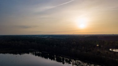 Göl kıyısında dramatik ve renkli bir gün batımının insansız hava aracı tarafından çekilen hava görüntüsü. Doğa manzarası. Avrupa 'da doğa. Yansıma, mavi gökyüzü ve sarı güneş ışığı. Gün doğumunda manzara veya