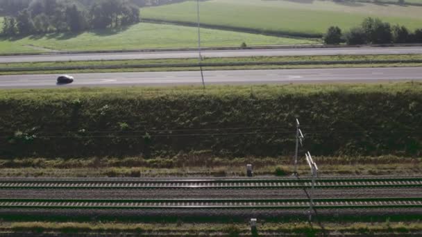 Vista aérea de drone voador de trilhos ferroviários ao lado de uma estrada com carros dirigindo nele — Vídeo de Stock