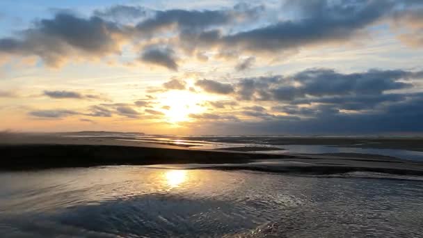 Incroyable coucher de soleil coloré avec des vagues venant sur une plage de sable fin à la mer sous un ciel peint avec des nuages et un soleil doré. Paysage naturel pittoresque. Nuages reflétés dans l'eau. Tranquille comme un zen — Video