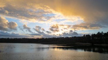 Gün batımında gölün üzerinde güzel, renkli bir gökyüzü. Huzurlu manzara, görünürde kimse yok. 