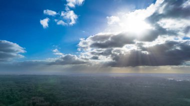 Kış güneşi bulutların arasından doğuyor, ağaçları ve tarlaları aydınlatıyor donuk ışıklarıyla donarak.