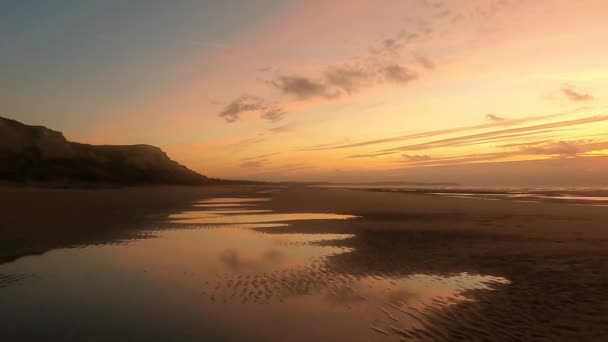 Incroyable coucher de soleil coloré avec des vagues venant sur une plage de sable fin à la mer sous un ciel peint avec des nuages et un soleil doré. Paysage naturel pittoresque. Nuages reflétés dans l'eau. Tranquille comme un zen — Video