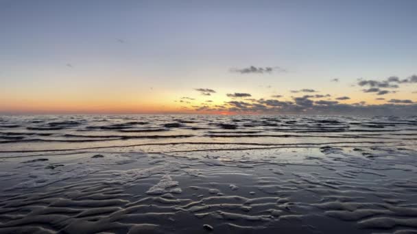 Belle plage de sable au coucher du soleil avec le ciel coloré reflété sur la plage et les vagues dans la mer — Video