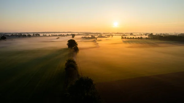 劇的な夏の日の出。パノラマ霧の風景。緑のフィールドと草原の空の景色の上に霧の朝。アスファルトの田舎の空の道路。ドローン農業写真ベラルーシ — ストック写真