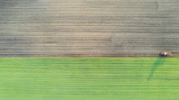 Aerial drone top view of a tractor with cultivator plowing field. Tractor disk harrow on ploughing a soil. Planting in farmland. Sowing seed on plowed field. Seeding in agriculture. Farm Machinery for — 스톡 사진