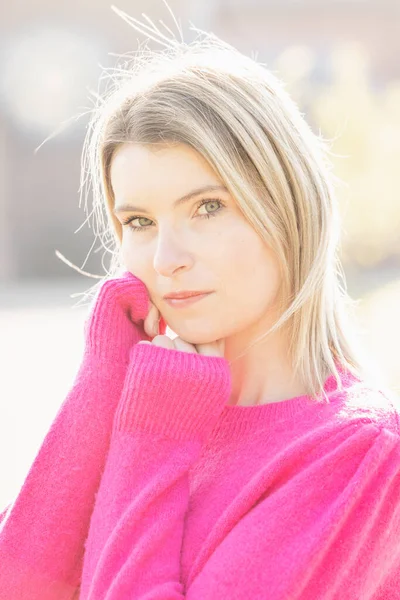 Portrait of a cute young blonde beautiful woman wearing a pink sweater, relaxed, cosy and happy in nature. — Photo
