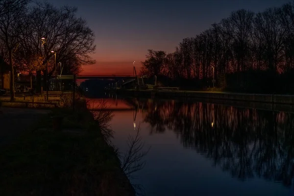 Río o canal al atardecer, sobre un fondo de árboles. Reflexión de la naturaleza sobre el agua — Foto de Stock