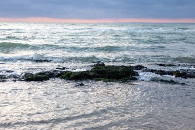 Pembe günbatımı dramatik mavi gökyüzü deniz suyu kaya taşından doğa manzarasına sıçrıyor. 