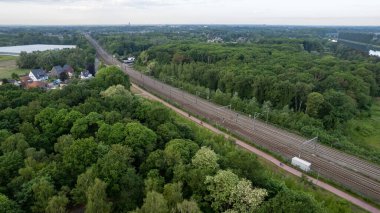 Yaz sabahı ormanı, gün doğumunda tren. Ormandaki demiryolu raylarının havadan görünüşü. Demiryolu yakınındaki en iyi hava aracı görüntüsü. Yüksek kalite fotoğraf