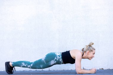 Çekici, sportif bir kadın spor yaparken spor salonuna konsantre oluyor. Genç mükemmel şekilli sarışın kalas yapıyor. Yüksek kalite fotoğraf
