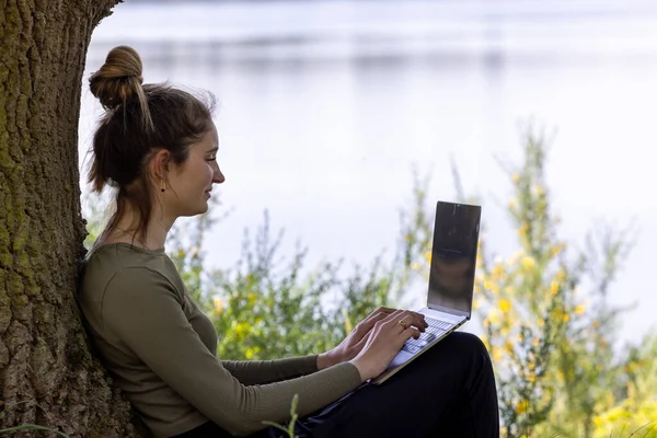 Work from anywhere. Remote freelancer work in nature. Young woman, female freelancer working with laptop with Beautiful view of forest and lake. freelancer paradise, freedom of teleworking. distance