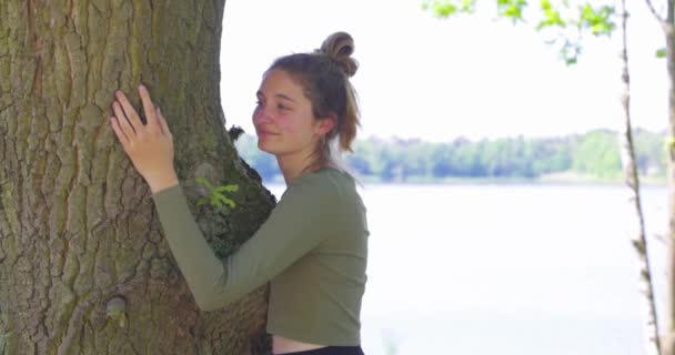 森を救う 森林破壊を止める 地球の日 自然とつながり 自然とつながり 自然を守るというコンセプトで 美しい表情と目を閉じた大きな木を抱いている若い女性 — ストック動画