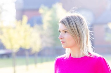 Güzel, çekici bir kızın portresi, yeşil renkli doğal arka planda pembe stil şık kıyafetler giyerek hafta sonunun tadını çıkarıyor. Yüksek kalite fotoğraf