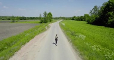 Sport woman running outdoor. woman jogging in rural area between the fields, aerial view. Back view of running people active training in park. fitness runner jogging outdoor. Sport people running in