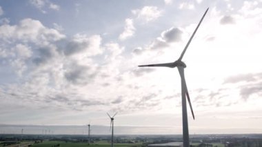 Aerial view of powerful Wind turbine farm for energy production on beautiful cloudy sky at highland. Wind power turbines generating clean renewable energy for sustainable development. 4k footage. High