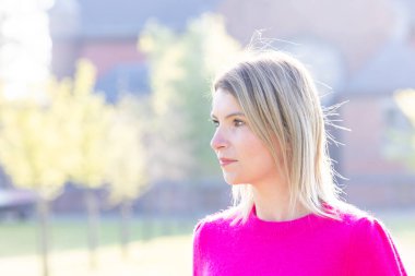 Güzel, çekici bir kızın portresi, yeşil renkli doğal arka planda pembe stil şık kıyafetler giyerek hafta sonunun tadını çıkarıyor. Yüksek kalite fotoğraf