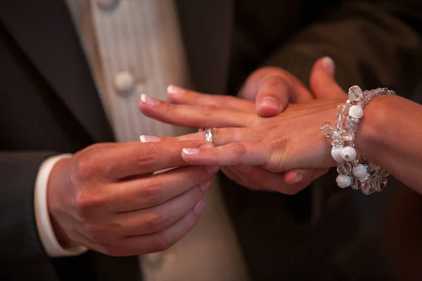 Close up of loving bride and groom putting a beautiful wedding ring to the beloved partner, marry me concept. High quality photo