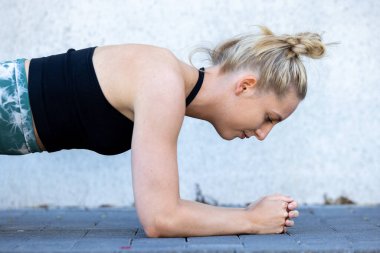 Çekici, sportif bir kadın spor yaparken spor salonuna konsantre oluyor. Genç mükemmel şekilli sarışın kalas yapıyor. Yüksek kalite fotoğraf