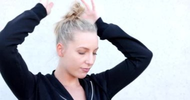 Portrait of beautiful, healthy, strong and fit young caucasian woman wearing a black hoodie flexing both arms muscles on white background. High quality 4k footage
