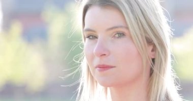 Front close up of caucasian woman, beautiful young human face with pale white skin and blonde hair, turning and looking at the camera smiling, open and confident. Portrait of European Belgian lady