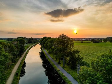 Colorful and dramatic sunset over the canal Dessel Schoten aerial photo shot by a drone in Rijkevorsel, kempen, Belgium, showing the waterway in the natural green agricultural landscape. High quality
