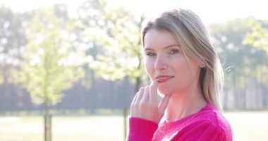 Beyaz tenli, sarışın, beyaz tenli, güzel bir insan yüzü olan beyaz bir kadının önünde kameraya şehvetle gülümseyen ve dudaklarına dokunarak kendinden emin bir şekilde bakıyor. & Portre