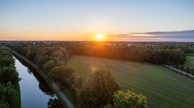 Colorful and dramatic sunset over the canal Dessel Schoten aerial photo shot by a drone in Rijkevorsel, kempen, Belgium, showing the waterway in the natural green agricultural landscape. High quality