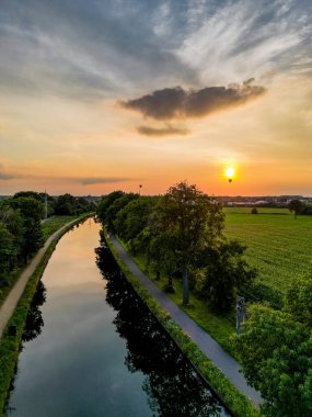 Colorful and dramatic sunset over the canal Dessel Schoten aerial photo shot by a drone in Rijkevorsel, kempen, Belgium, showing the waterway in the natural green agricultural landscape. High quality
