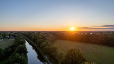 Colorful and dramatic sunset over the canal Dessel Schoten aerial photo shot by a drone in Rijkevorsel, kempen, Belgium, showing the waterway in the natural green agricultural landscape. High quality