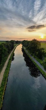 Colorful and dramatic sunset over the canal Dessel Schoten aerial photo shot by a drone in Rijkevorsel, kempen, Belgium, showing the waterway in the natural green agricultural landscape. High quality