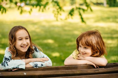 Uzun saçlı küçük bir oğlan ve bir kız parkta bir bankta oturuyor. Çocuklar bankta bir paketin içinde otururken konuşurlar. Oğlan ve kız boş zamanlarını dışarıda geçirirler. Bir kız ve bir erkek portresi.