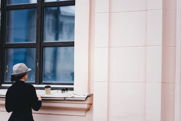 Atrakcyjna Dziewczyna Ciemnobrązowymi Włosami Kapeluszu Wygląda Przez Okno Instytucji Podczas — Zdjęcie stockowe