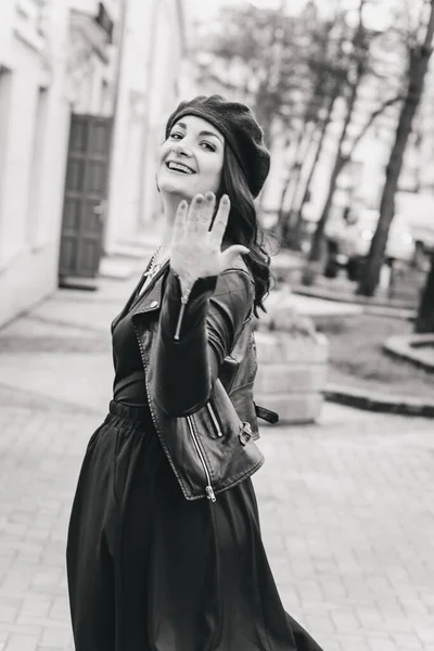 一个穿着皮夹克 头戴贝雷帽 身穿黑色长裙 面带微笑的女孩的画像 躺在城市的街道上 时尚与时尚的概念 笑得开心的女孩 — 图库照片