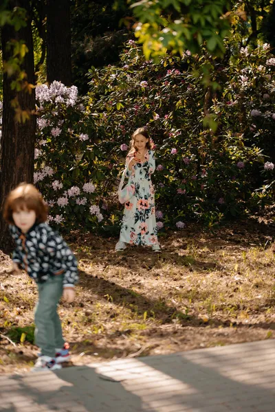 小さな女の子と男の子が花や木 植物園の間で公園を歩いています 男の子と女の子過ごす彼らの自由な時間屋外 — ストック写真