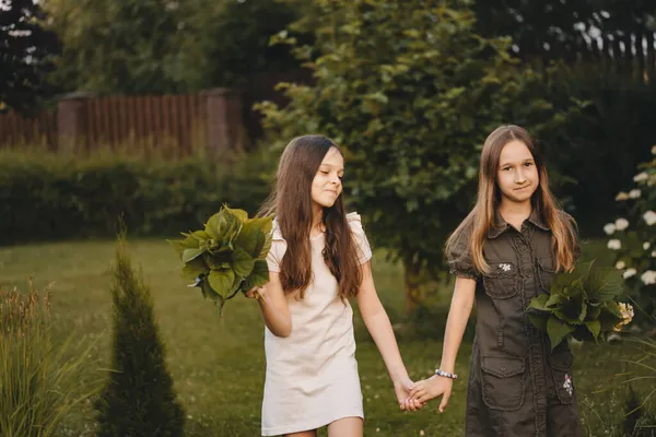 Две Девушки Элегантных Платьях Гуляют Зеленом Парке Держась Руки Красивый — стоковое фото