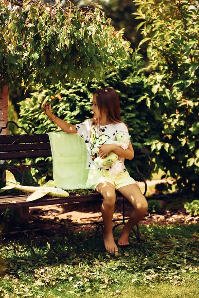 Uma Menina Uma Saia Senta Banco Parque Verão Com Brinquedo — Fotografia de Stock