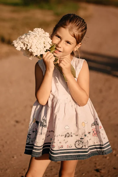 Piękna Dziewczynka Jasnej Letniej Białej Sukience Pozuje Zewnątrz Słońcu Bukietem — Zdjęcie stockowe