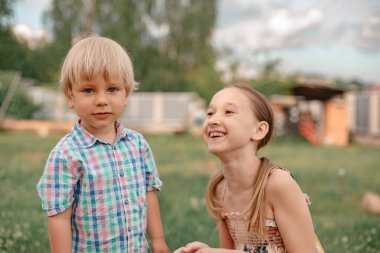 Portrait of little boy and girl walking in the park, nice summer weather. Carefree childhood. Brother and sister have fun outdoors together. Little boy with blond hair and blue eyes.
