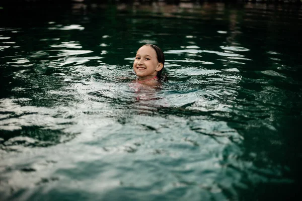 一个穿着粉色游泳衣的微笑的小女孩在湖中的新鲜空气中游泳 乡间的一个池塘 健康生活方式和多样性概念 — 图库照片