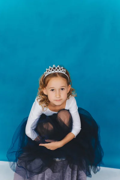 Girl Magnificent Dress Sits Background Blue Wall Happy Little Girl — Stock Photo, Image