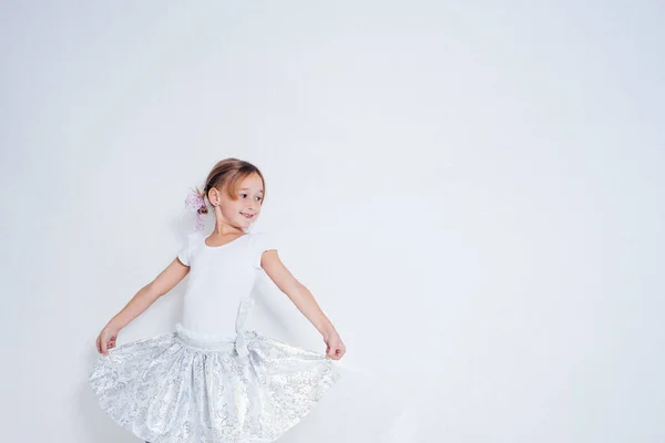 白いドレスの少女は 背景に踊っている白い背景です 幸せな女の子笑顔 素晴らしい時間を持っている 子供のスタイルとファッションの概念 コピースペース トーニング — ストック写真