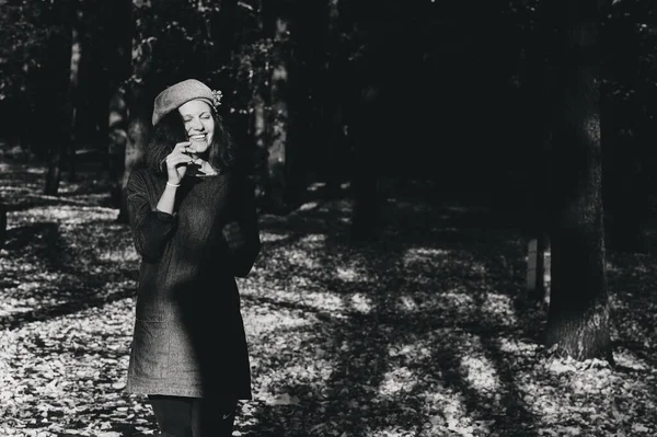 一个头戴贝雷帽 身穿外套的快乐女孩走在秋天的公园里 秋天的树叶落在地上 — 图库照片